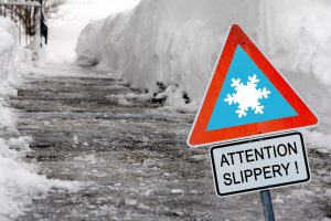 Attention Slippery sign on an icy walkway, highlighting the potential hazards of winter conditions for pedestrians.